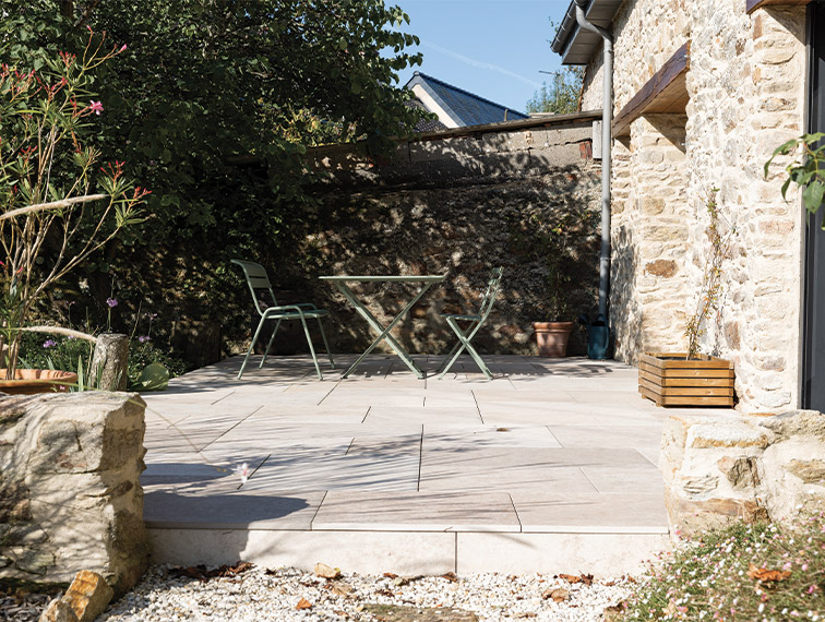 Terrasse en dalle beige permettant un espace repas, maison en pierre